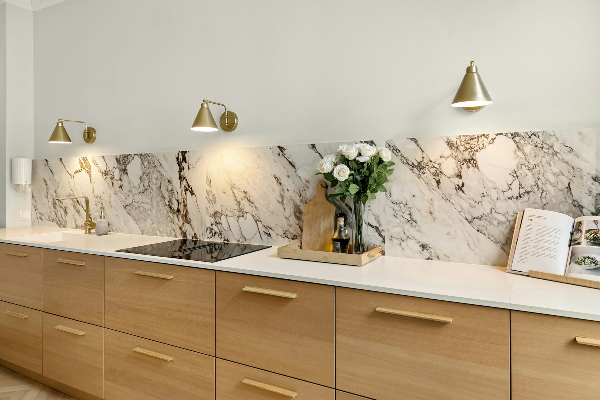 Marble splashback with brass lighting above a timber kitchen