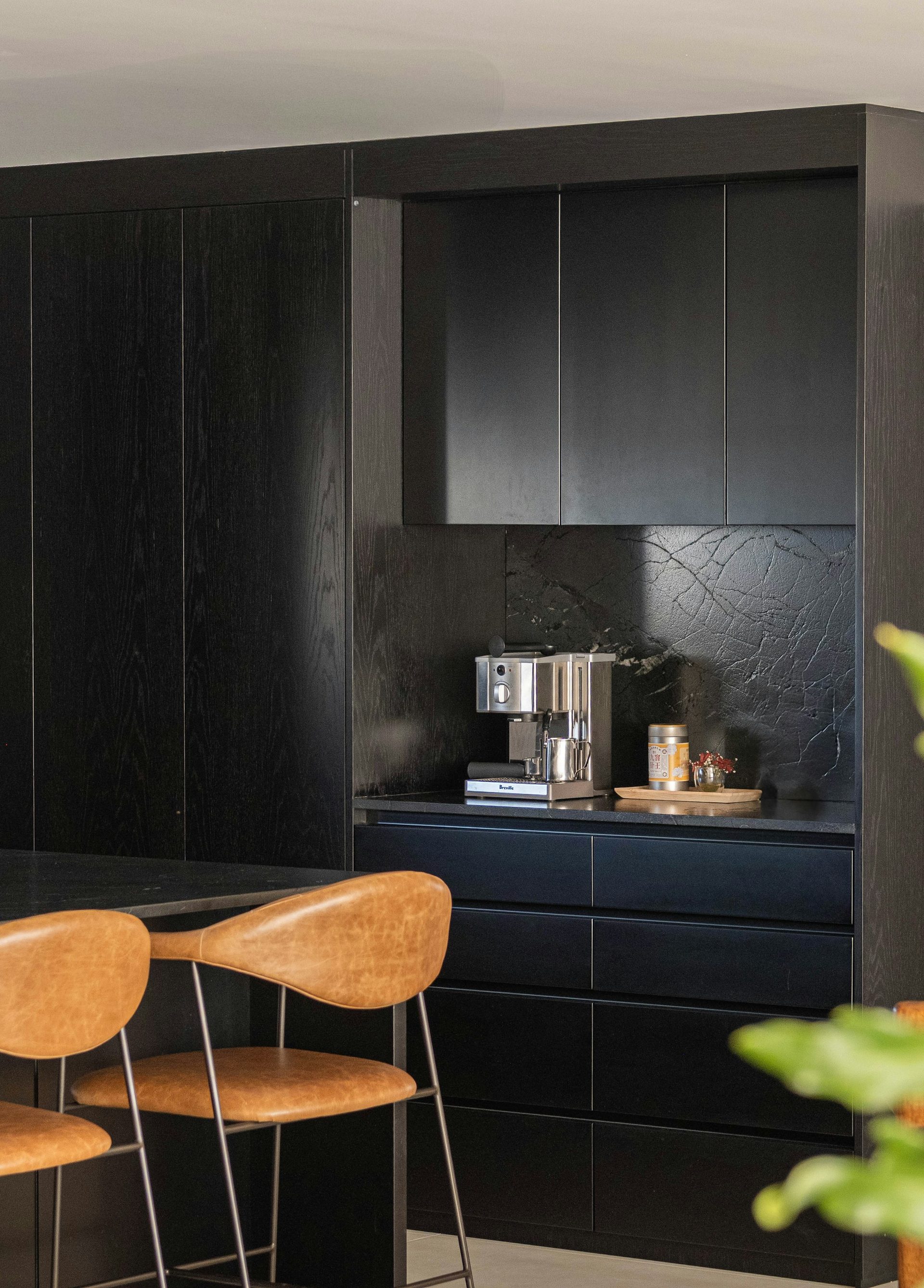 Dark kitchen with an integrated coffee station behind a lift door, cabinetry delivered assembled